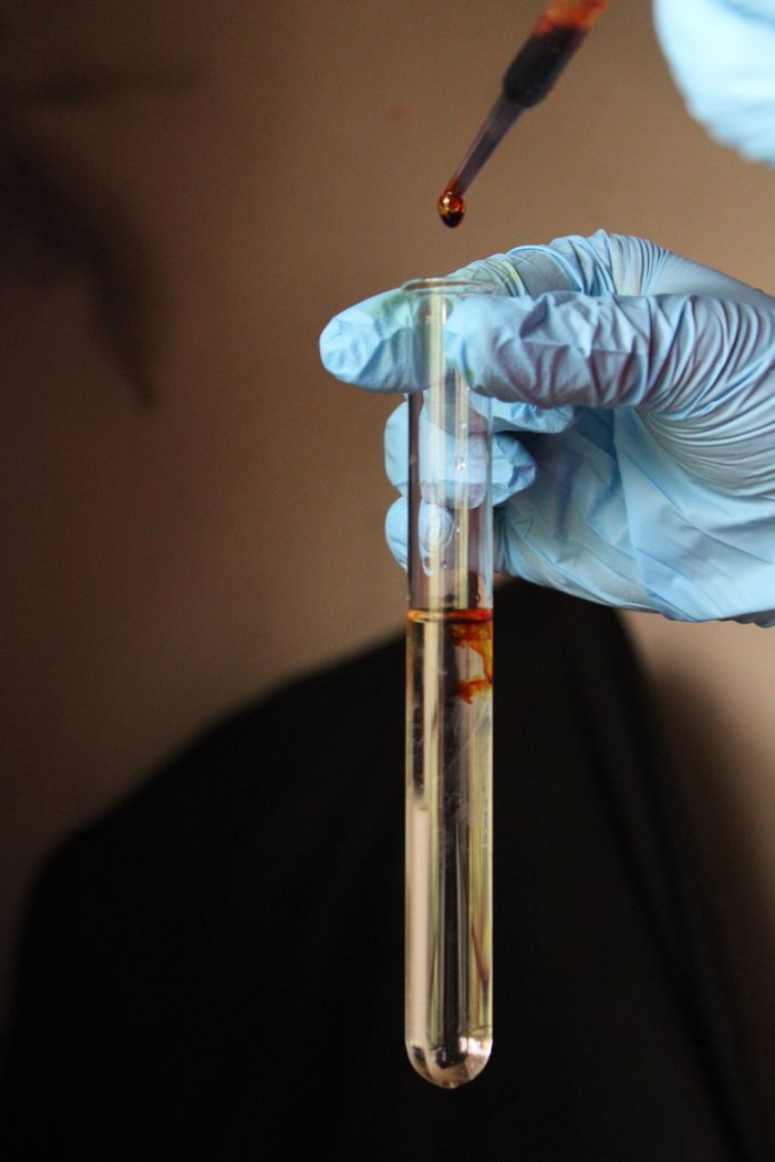 About Close-up of a gloved hand adding liquid to a test tube, highlighting a scientific experiment.